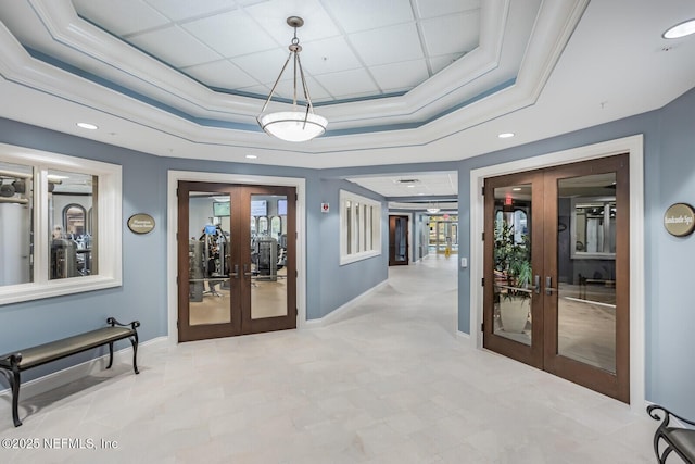 hallway featuring french doors, a raised ceiling, and ornamental molding