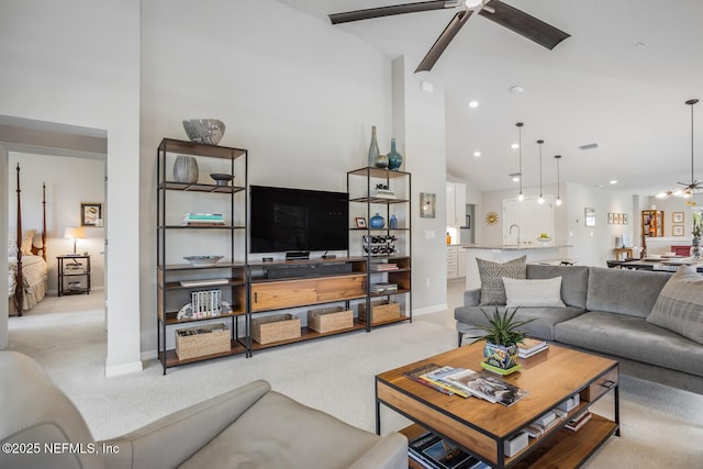 carpeted living room with high vaulted ceiling, ceiling fan, and sink