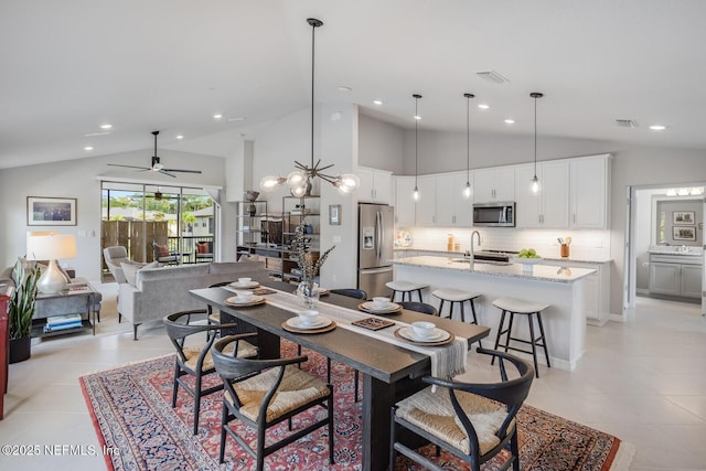 tiled dining area with ceiling fan with notable chandelier, high vaulted ceiling, and sink