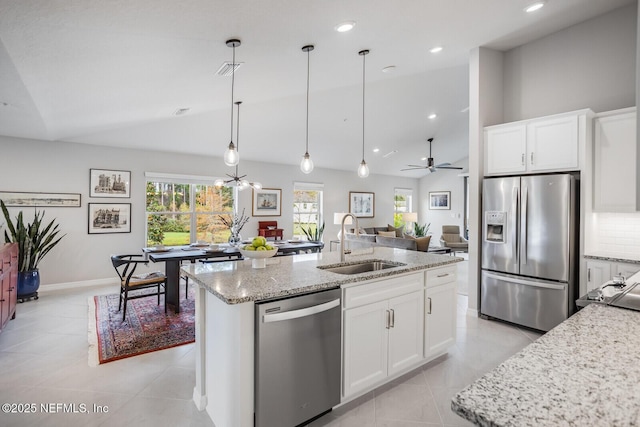 kitchen with appliances with stainless steel finishes, white cabinetry, vaulted ceiling, and sink