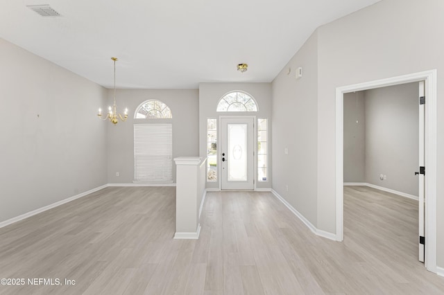 entrance foyer featuring a healthy amount of sunlight, light wood-type flooring, and a notable chandelier