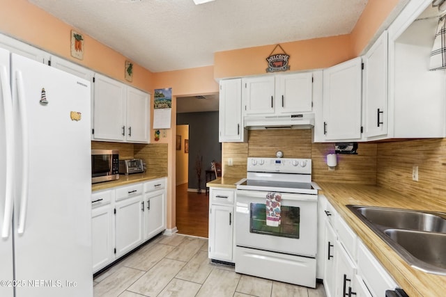 kitchen with a textured ceiling, backsplash, white cabinets, and white appliances