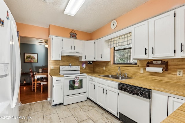 kitchen featuring sink, white cabinetry, a textured ceiling, light tile patterned floors, and white appliances