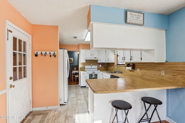 kitchen with white cabinetry, sink, decorative backsplash, kitchen peninsula, and white appliances