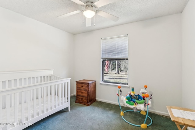 carpeted bedroom featuring a textured ceiling, a nursery area, and ceiling fan