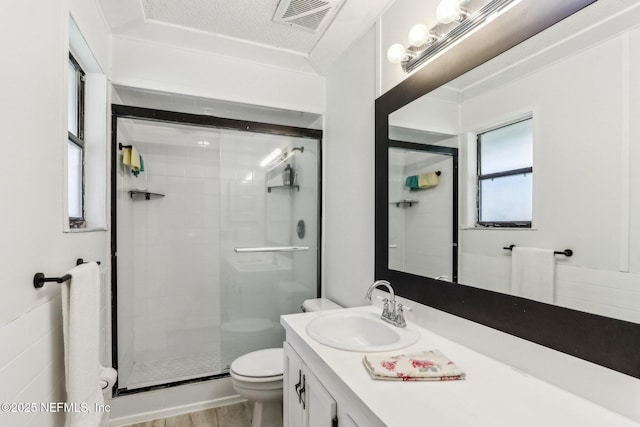 bathroom with hardwood / wood-style floors, vanity, an enclosed shower, toilet, and a textured ceiling