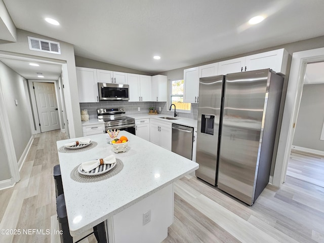 kitchen featuring appliances with stainless steel finishes, sink, white cabinets, a kitchen island, and lofted ceiling