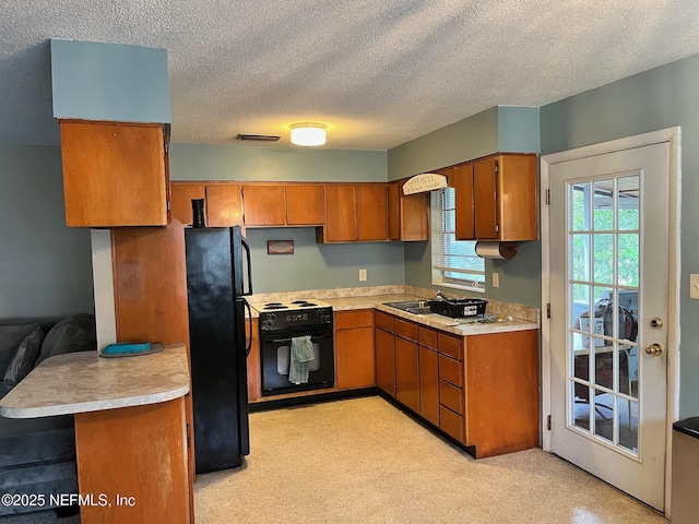 kitchen with black appliances, kitchen peninsula, sink, and a textured ceiling