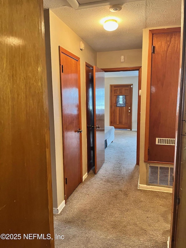 hallway with light carpet and a textured ceiling