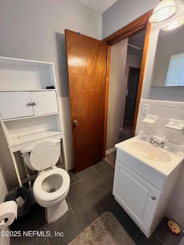 bathroom with tile walls, toilet, vanity, and tile patterned flooring