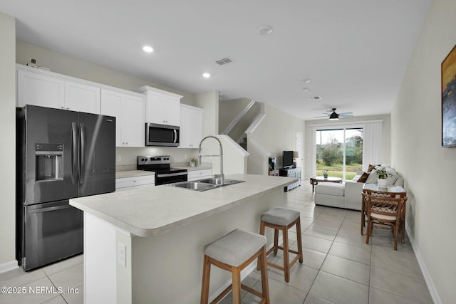 kitchen featuring white cabinets, appliances with stainless steel finishes, a center island with sink, and sink