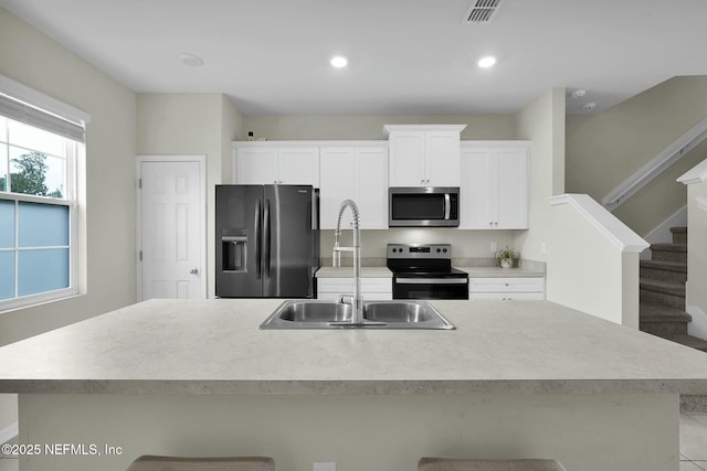 kitchen featuring sink, stainless steel appliances, white cabinets, an island with sink, and light tile patterned flooring