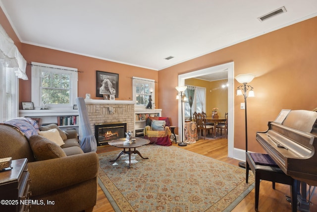 living room featuring crown molding, light hardwood / wood-style floors, and a brick fireplace