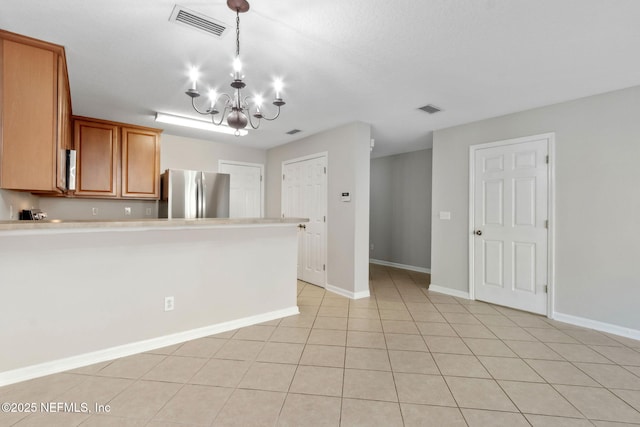 kitchen featuring light tile patterned flooring, a notable chandelier, stainless steel fridge, and hanging light fixtures