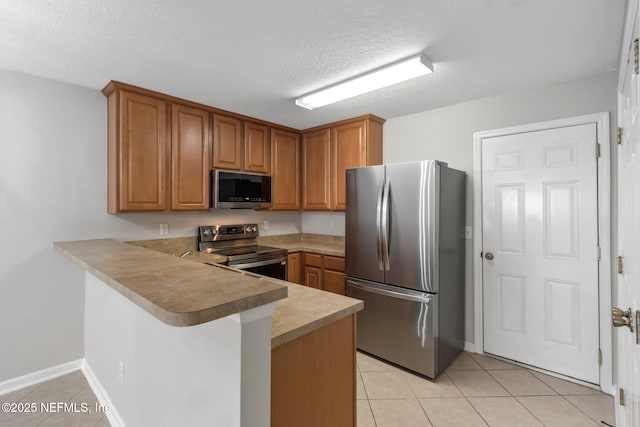 kitchen with kitchen peninsula, light tile patterned floors, stainless steel appliances, and a textured ceiling