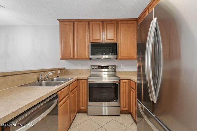 kitchen featuring sink, a textured ceiling, light tile patterned floors, and stainless steel appliances