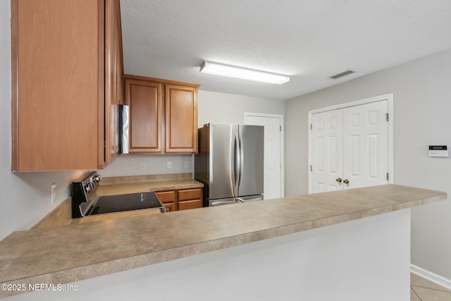 kitchen with stainless steel appliances, kitchen peninsula, a textured ceiling, and light tile patterned flooring