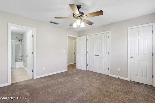 unfurnished bedroom with light carpet, multiple closets, ensuite bath, and ceiling fan