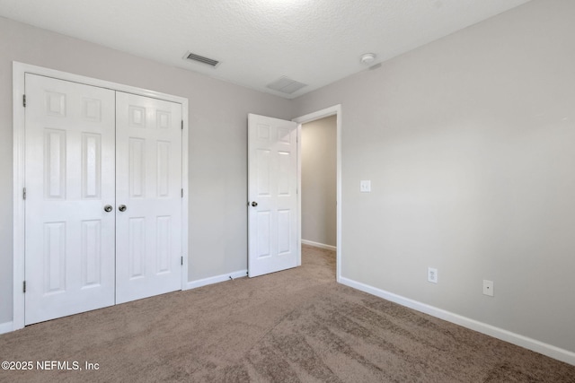 unfurnished bedroom with a textured ceiling, a closet, and carpet flooring