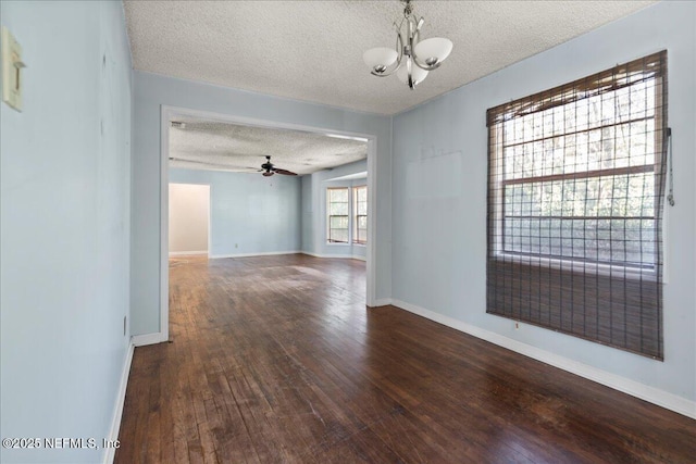 spare room featuring dark hardwood / wood-style flooring, ceiling fan with notable chandelier, and a textured ceiling