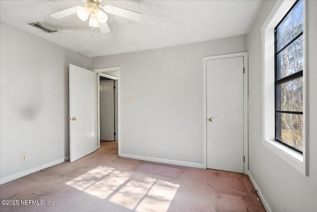 unfurnished bedroom featuring light carpet, a textured ceiling, and ceiling fan