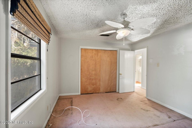 unfurnished bedroom with ceiling fan, a closet, light carpet, and a textured ceiling