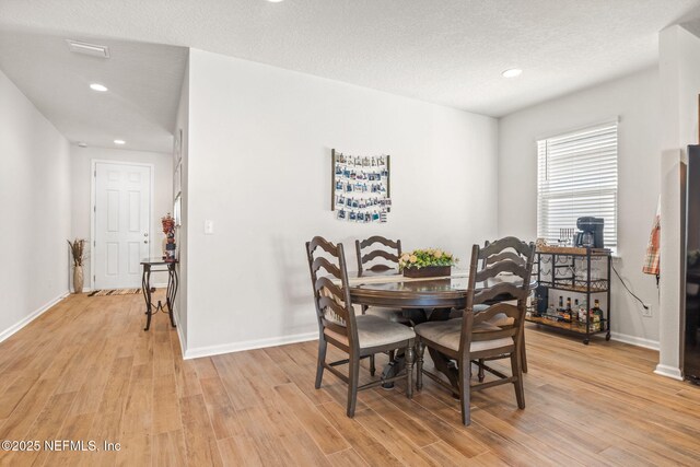 dining area with light hardwood / wood-style floors and a textured ceiling