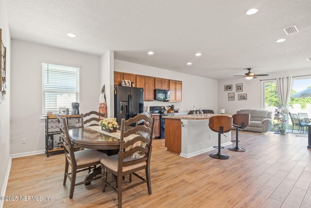 dining area featuring ceiling fan, light wood-type flooring, and a textured ceiling