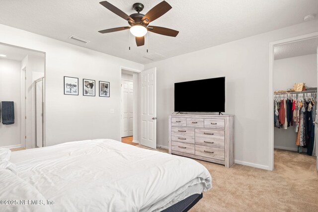 carpeted bedroom featuring ceiling fan, a walk in closet, and a closet