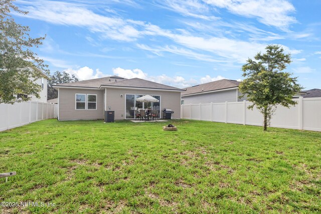 rear view of property featuring central AC, a fire pit, and a lawn