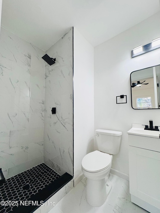 bathroom with a tile shower, ceiling fan, vanity, and toilet