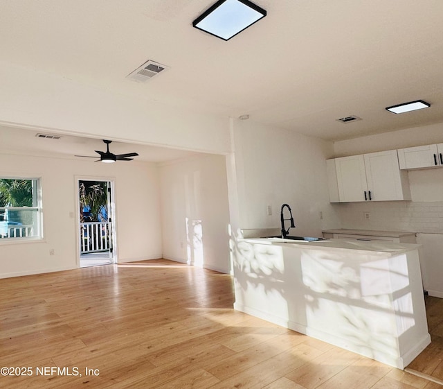 kitchen with white cabinets, ceiling fan, sink, and light hardwood / wood-style flooring