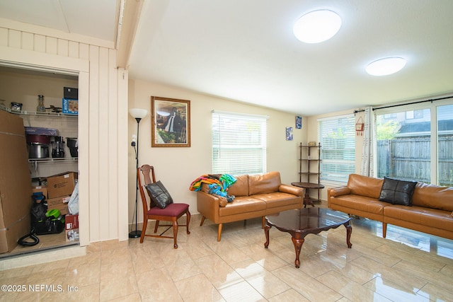 living room with light tile patterned floors, lofted ceiling with beams, and a healthy amount of sunlight