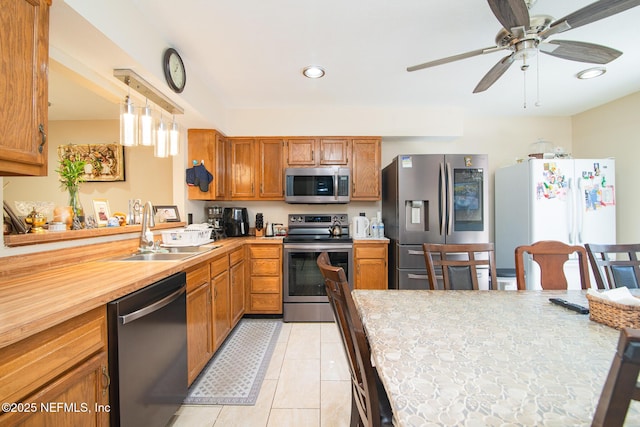 kitchen featuring stainless steel appliances, ceiling fan, sink, hanging light fixtures, and light tile patterned flooring