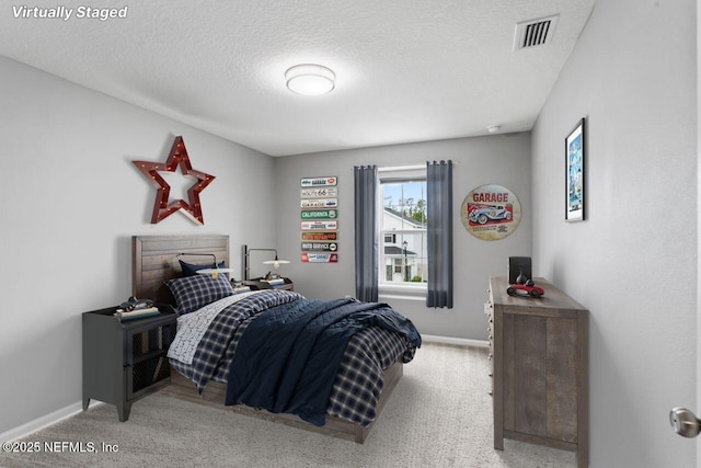 bedroom with light colored carpet and a textured ceiling