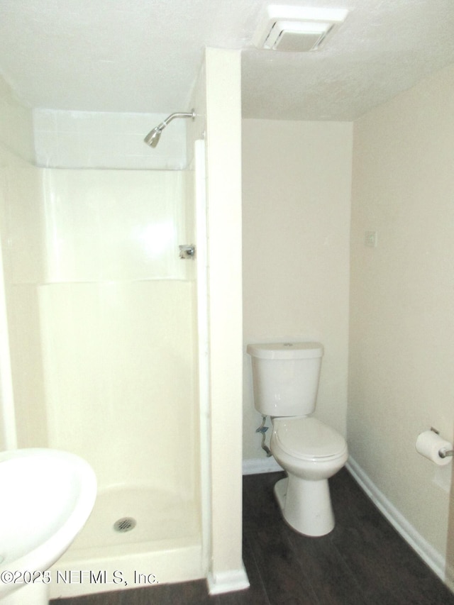 bathroom with toilet, wood-type flooring, and walk in shower