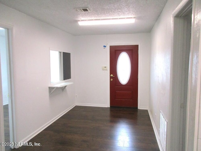 foyer entrance with dark hardwood / wood-style flooring and a textured ceiling