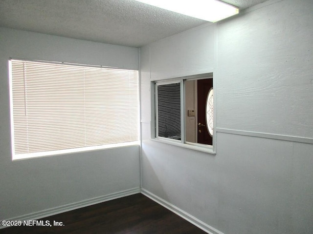 spare room with dark wood-type flooring and a textured ceiling