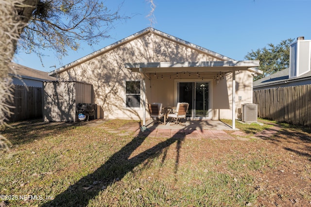 rear view of house with central AC unit, a shed, a patio area, and a yard