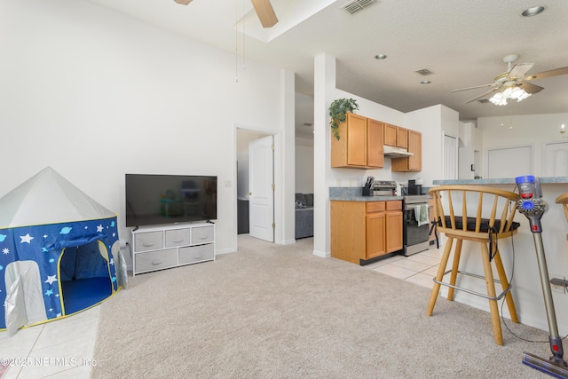 kitchen with ceiling fan, a breakfast bar, stainless steel electric stove, and light colored carpet