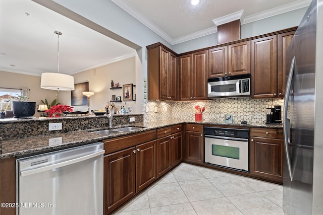 kitchen with decorative light fixtures, stainless steel appliances, dark stone countertops, and sink