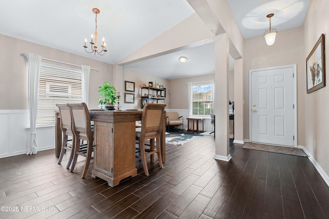 dining area with dark wood-type flooring, lofted ceiling, and a chandelier