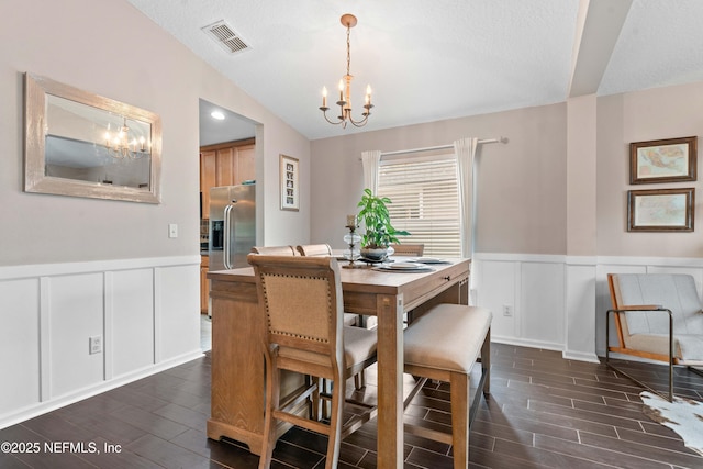 dining room featuring an inviting chandelier, lofted ceiling, and a textured ceiling