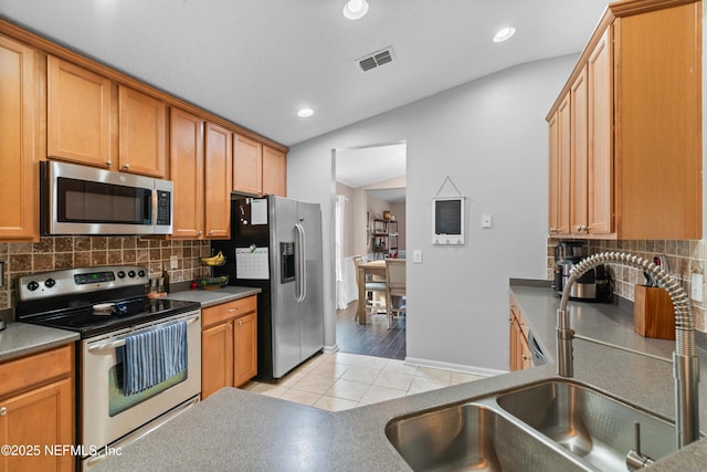 kitchen with backsplash, appliances with stainless steel finishes, sink, and light tile patterned floors