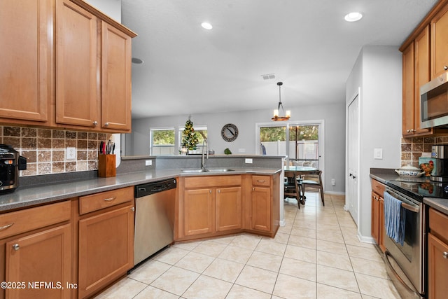 kitchen featuring light tile patterned flooring, stainless steel appliances, decorative light fixtures, and a wealth of natural light