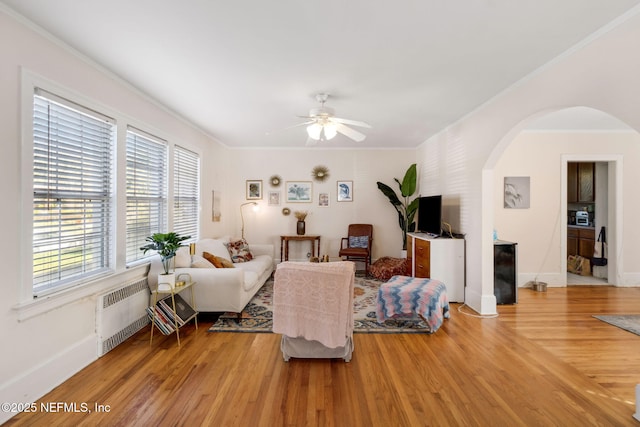 living room featuring hardwood / wood-style floors, ceiling fan, ornamental molding, and radiator