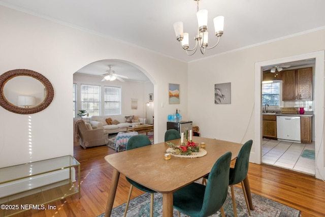 dining room featuring hardwood / wood-style flooring, ceiling fan with notable chandelier, ornamental molding, and sink