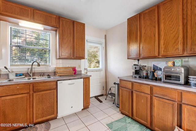 kitchen with dishwasher, decorative backsplash, sink, and light tile patterned floors