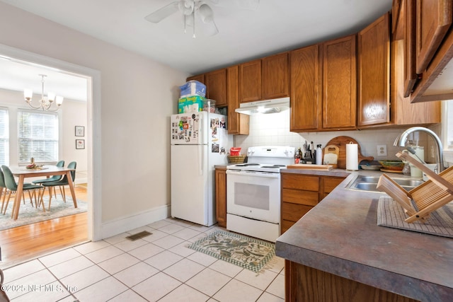 kitchen with sink, hanging light fixtures, white appliances, light tile patterned floors, and ceiling fan with notable chandelier