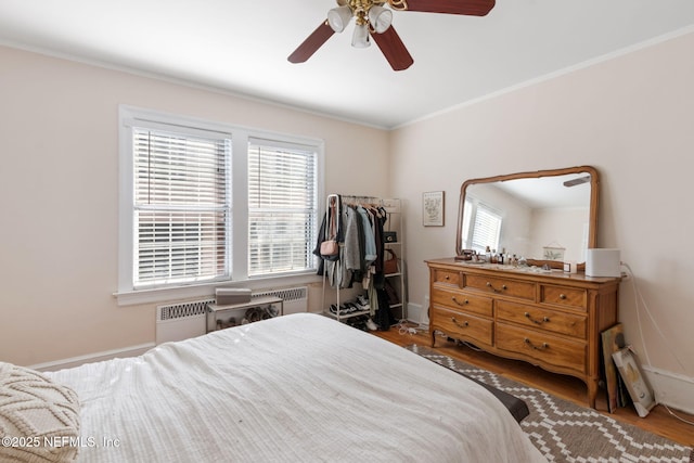 bedroom featuring hardwood / wood-style floors, ceiling fan, ornamental molding, and radiator